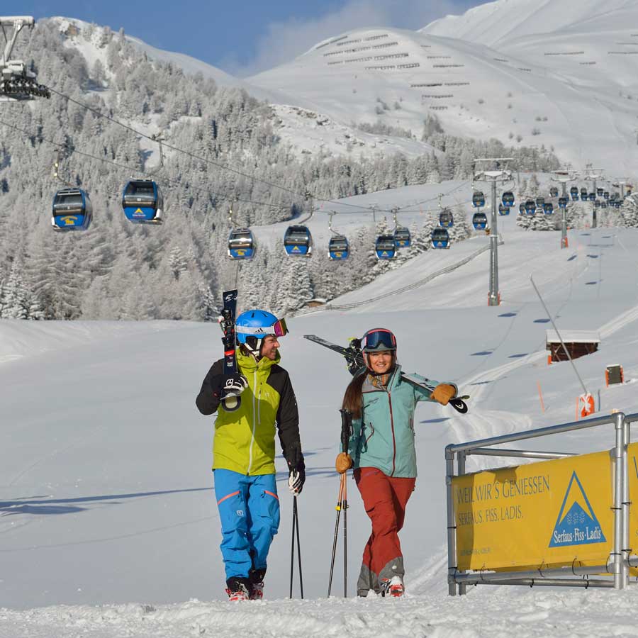 Two skiers with skis near lifts, ready for 3 fun ski days incl. 2-day ski pass.