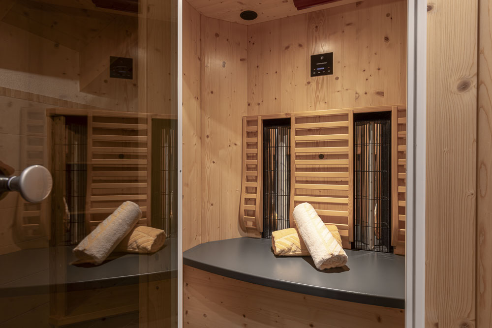 Kleine Holzsauna mit einer Bank und zwei gerollten Handtüchern darauf.