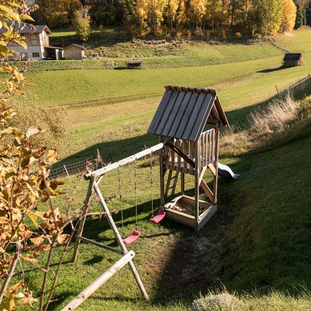 Holzspielgerät mit Schaukel und Rutsche in der privaten Gartenspa im Edelweiss Chalet in Ladis.